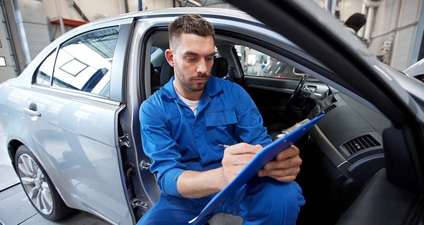 Mechanic in a car checking off a clipboard